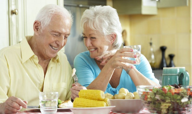 Older couple eating vegetables in a bright room